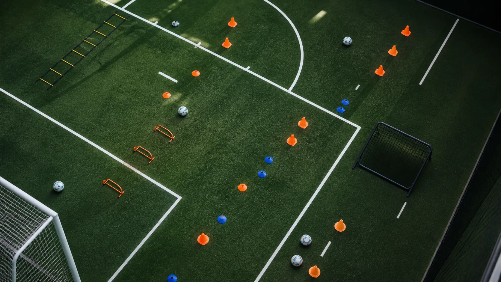 Overhead view of a soccer training setup with cones, balls, ladders, and rebound equipment.